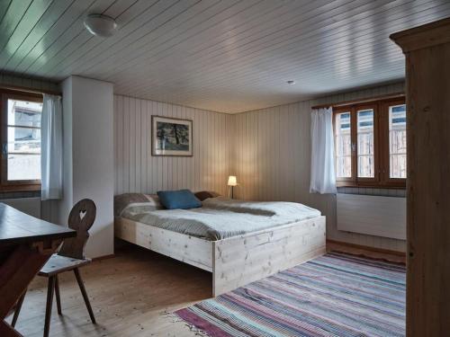 a bedroom with a bed and a desk and windows at Cosy traditional mountain house in scenic valley in Cumbels