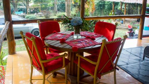 un tavolo con sedie rosse e un vaso di fiori di Neysa's Vacation House a Los Naranjos