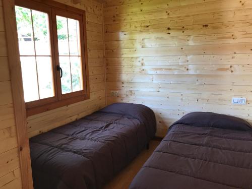2 camas en una cabaña de madera con ventana en Bungalows - Càmping El Solsonès, en Solsona