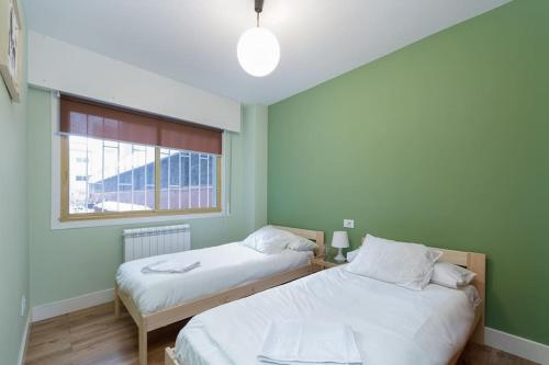 two beds in a room with green walls and a window at Con parking gratis en el centro by CABANA Rentals in Vigo