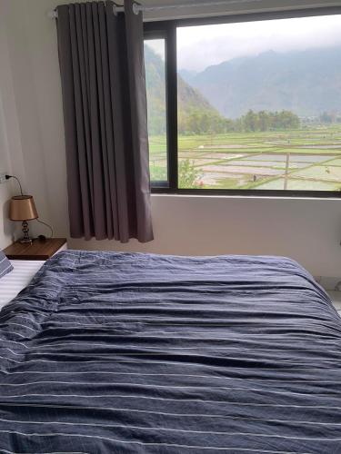 a bed in a bedroom with a large window at Mai chau Horizon Homestay in Mai Chau