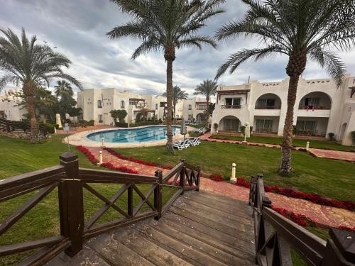 Private Luxury Villas at Sharm Dreams Resort في شرم الشيخ: ممشى خشبي يؤدي إلى منتجع فيه أشجار نخيل