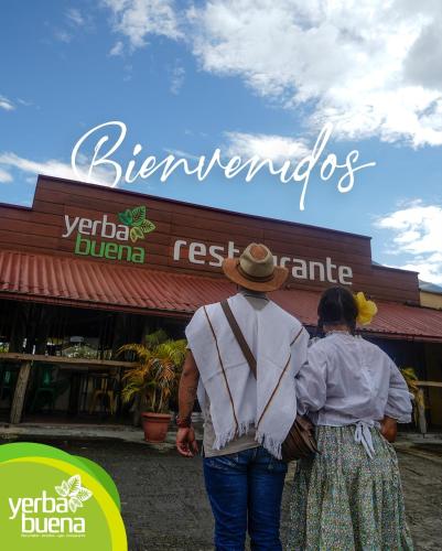 a man and a woman standing in front of a store at Finca Hotel Yerbabuena in Pereira