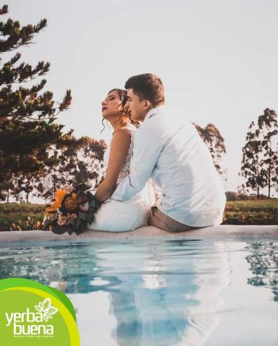 a bride and groom sitting on the edge of a swimming pool at Finca Hotel Yerbabuena in Pereira