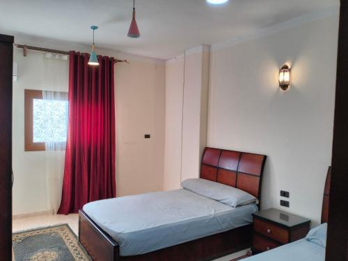 een slaapkamer met een bed en een rood gordijn bij Nile House in Abu Simbel