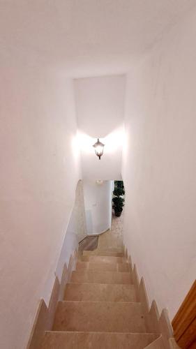 Un escalier avec des murs blancs et une lumière au-dessus dans l'établissement La casita del arco, à Santa Cruz de la Zarza