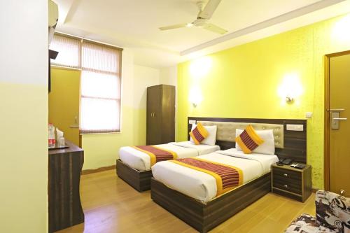 2 camas en una habitación de hotel con paredes amarillas en Hotel Amenda Delhi IGI Airport International Mahipalpur, en Nueva Delhi
