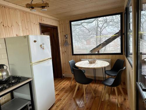uma cozinha com um frigorífico, uma mesa e cadeiras em Cozy Wooden House in Kiket'i კიკეთი em Kiketʼi