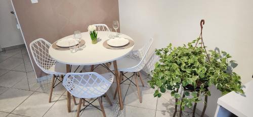 a white dining room table with white chairs and plants at 50 m do mar, 3 dorm, sacada com vista mar, pitangueiras, vaga de garagem, Pet friendly, berço in Guarujá