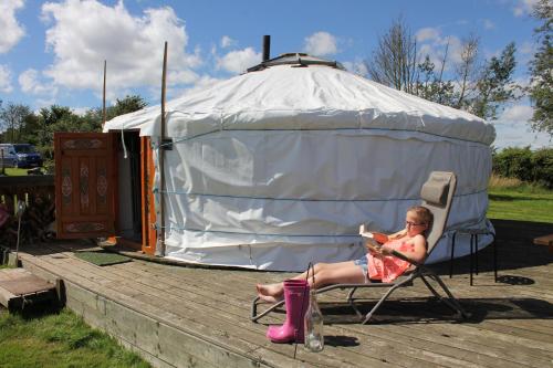 Glamping West Midlands في Enville: امرأة تجلس على كرسي أمام يورت