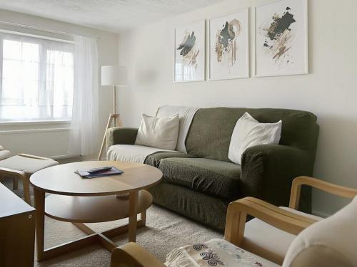 a living room with a green couch and a table at Private guest house - Double bedroom, en-suite and workspace with private entrance, first floor with no lift and no full kitchen in Leicester