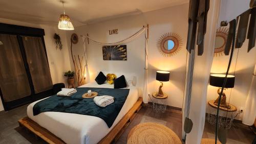 a bedroom with a bed with towels and two lamps at TOPAZE Nuitée Romantique avec Jacuzzi in Moyvillers
