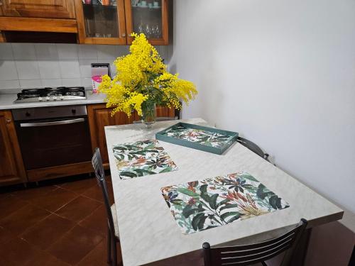 a kitchen table with a vase of yellow flowers on it at IL PEPE ROSA di Anna e Silvano in Sarzana