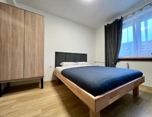 a bedroom with a bed and a wooden cabinet at K22 Airport Chopin Apart B in Warsaw