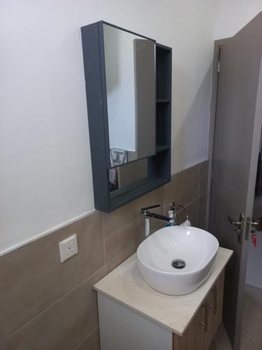 a bathroom with a white sink and a mirror at Kensington Square Luxury Apartment in Flic-en-Flac