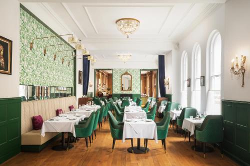 a dining room with white tables and green chairs at The Bailey's Hotel London Kensington in London