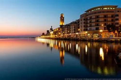 a view of a building and the water at night at Maison appartaments in Bari