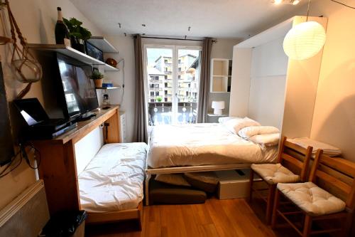 ein kleines Schlafzimmer mit einem Bett und einem Fenster in der Unterkunft Cozy Chamonix Ski Studio with Mountain Views in Chamonix-Mont-Blanc