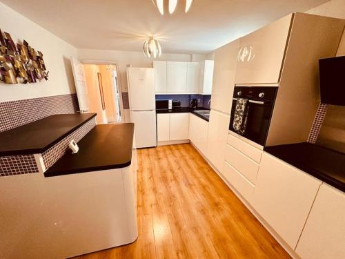 a kitchen with white appliances and a wooden floor at Winter Gardens Large Flat 1 in Blackpool