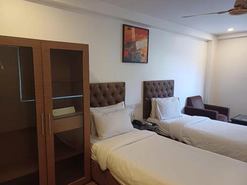 a hotel room with two beds and a chair at Hotel Marina Inn Egmore Chennai in Chennai