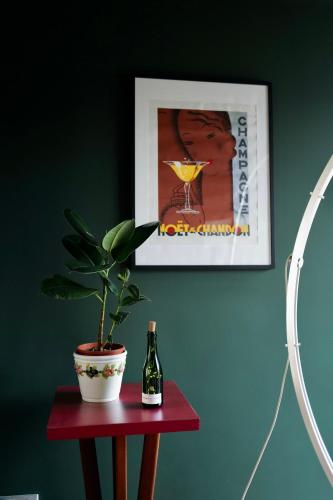 eine Topfpflanze auf einem Tisch mit einer Flasche Wein in der Unterkunft Maison au cœur des vignes in Épernay