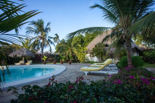 a swimming pool with two lounge chairs and palm trees at Villa Marine Park - Malindi in Malindi