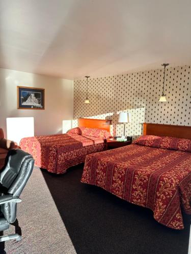 una habitación de hotel con dos camas y una silla en White River Motel, en White River