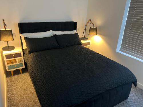 1 cama en un dormitorio con 2 lámparas en 2 mesas en Newly Renovated Apartment, en Bicester