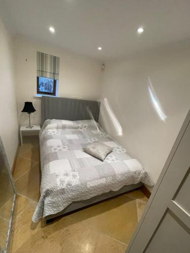 a bed in a white room with a window at Little Kent End Cottage in Ashton Keynes