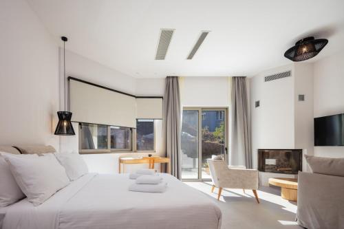 una camera bianca con un grande letto e una sedia di Panorama Luxury Suites a Spílion
