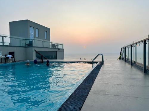 a swimming pool next to the ocean with people in it at Ocean Breeze Hotel Residencies BritLanka Apartments Negombo in Negombo