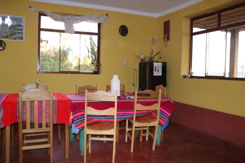 comedor con mesa roja y sillas en SUNSET Lodge Amantani, en Ocosuyo