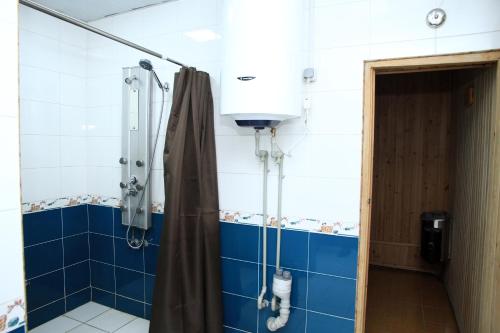 a shower in a bathroom with blue tiles at Yellow Hostel Dushanbe in Dushanbe