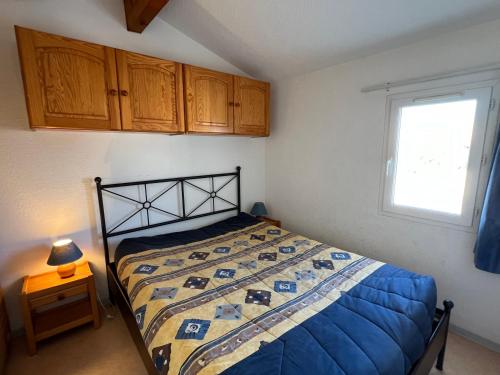 une chambre avec un lit avec une couette bleue et une fenêtre dans l'établissement LAVANDINES II Joli T3 mezzanine villa mitoyenne piscine proche plage Rochelongue Cap d'Agde, au Cap d'Agde