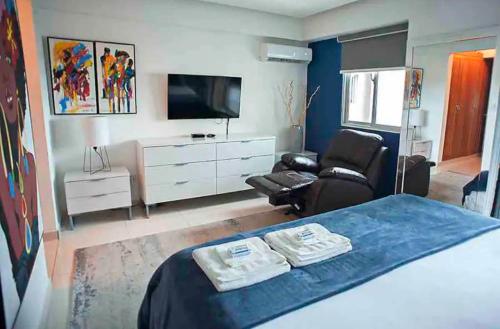 1 dormitorio con 1 cama, TV y silla en Oceanview Artisans Relax, en Santo Domingo