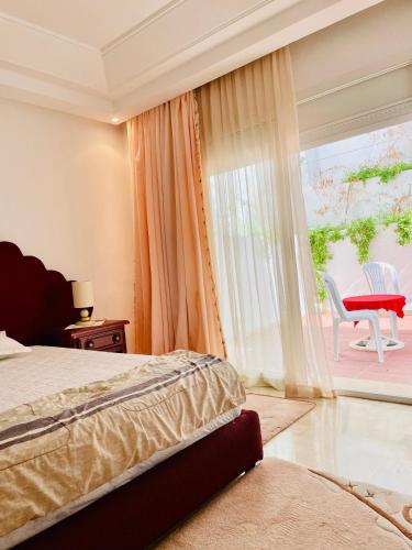 1 dormitorio con 1 cama y ventana con silla en Superbe villa meublée Ennacer 95€/j, en Burj at Turkī