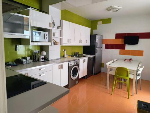 uma cozinha com armários brancos e uma pequena mesa com uma mesa em Casa El limonero em Sevilha