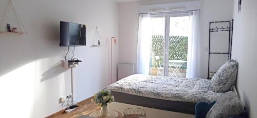 a small bedroom with a bed and a window at Petite touche douceur - studio avec parking et terrasse in Suresnes