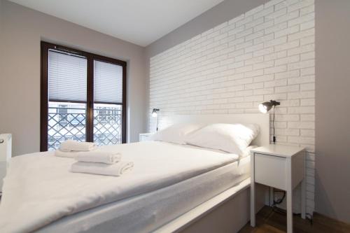 a white bedroom with a white brick wall at Apartament Great koło opery i miejscem postojowym w garażu in Białystok