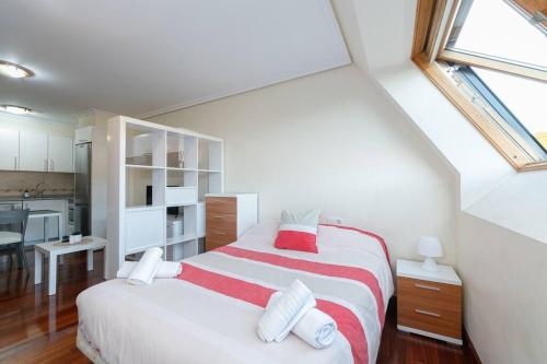 a white bedroom with a large bed and a kitchen at Luminoso ático para dos by CABANA Rentals in Vigo