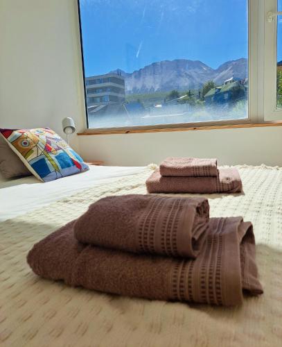 a bedroom with two towels on a bed with a window at Lo de Gaston in Ushuaia