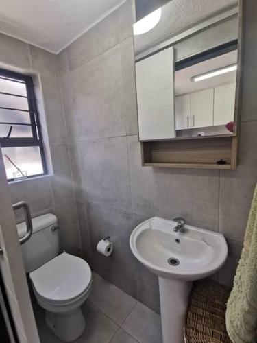 a small bathroom with a toilet and a sink at Kingfisher Cottage in Ballito