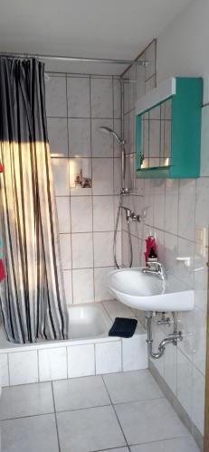 ein Badezimmer mit einem Waschbecken, einer Badewanne und einer Dusche in der Unterkunft Ferienwohnung Clauss in Zwiefalten