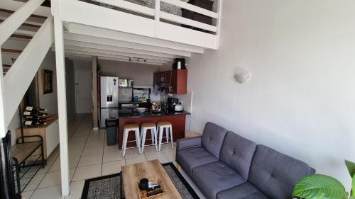 uma sala de estar com um sofá e uma cozinha em Urben Loft - Back up Power na Cidade do Cabo