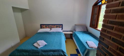 a small room with two beds and a window at Chalés Canton Suisse in Nova Friburgo