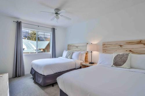 a bedroom with two beds and a window at Big Mountain Views - 2-story Corner Unit in Canmore