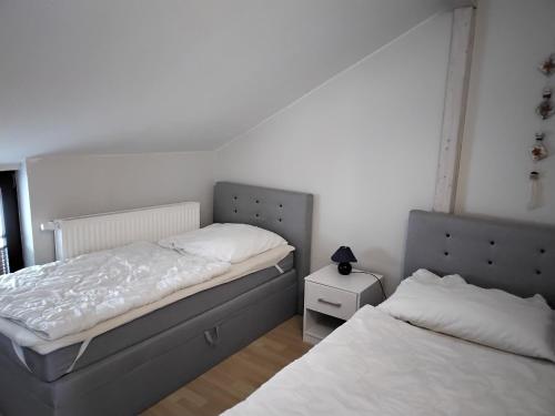 a bedroom with two beds and a night stand at Ferienwohnung Neptun am Brunnenplatz Zentrum in Büsum