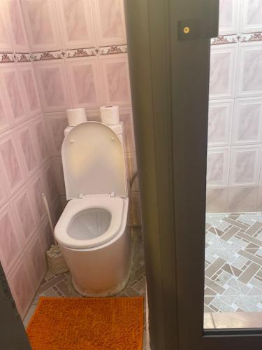 a bathroom with a toilet in a pink room at Villa de chez nous in North Legon