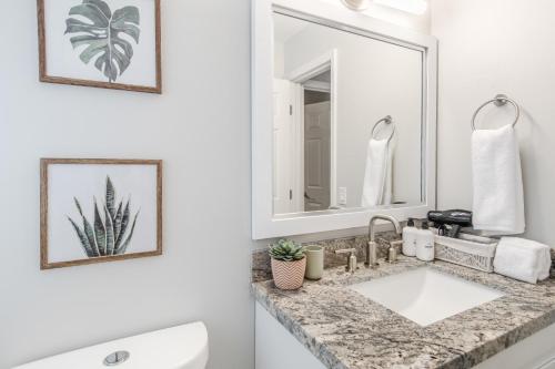 La salle de bains blanche est pourvue d'un lavabo et d'un miroir. dans l'établissement 10 Mins to Beach - 2BR Private Pool + Spa + Grill, à Vero Beach
