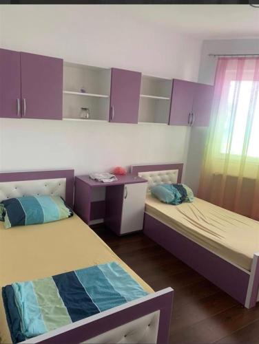 2 Betten in einem Zimmer mit lila Schränken in der Unterkunft Besmir in Pristina
